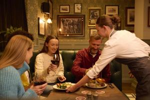 a woman serving a group of people at a table in a restaurant at The Kingslodge Inn - The Inn Collection Group in Durham