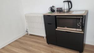a microwave on a stand next to a radiator at Chambre 8 in Le Trait