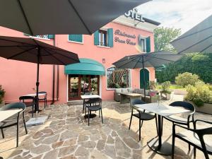 eine Terrasse mit Tischen und Sonnenschirmen vor einem Gebäude in der Unterkunft Hotel Gran Casa in Oderzo