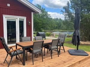 a wooden table with chairs and an umbrella on a deck at Lake House Rågeboda in Södra Rågeboda