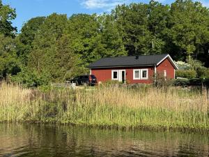 a red house in a field next to a body of water at Lake House Rågeboda in Södra Rågeboda