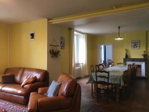 a living room with a leather couch and a table at La maison des ponts in Pont-sur-Madon