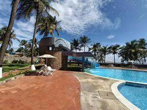 a swimming pool with palm trees and a building at Nautilus suites in Tucacas