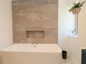 a bath tub in a bathroom with a tile wall at Cern-Wyn in Chippenham +37 photos