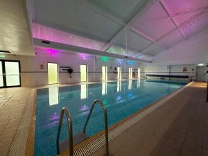 a large indoor swimming pool with purple lights at De Vere Wokefield Estate in Reading