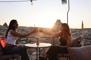 two women sitting at a table with a drink at Castle Cave Hotel in Göreme
