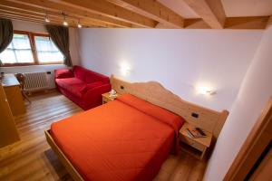 a bedroom with an orange bed and a red couch at Albergo al Fontanin in Rabbi
