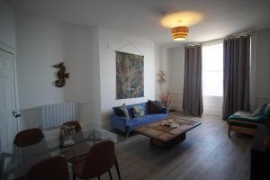 a living room with a blue couch and a table at Ground floor sea view flat Hastings in Hastings +1 photo