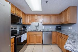 a kitchen with wooden cabinets and a sink at Phoenix VII 7709 condo in Orange Beach