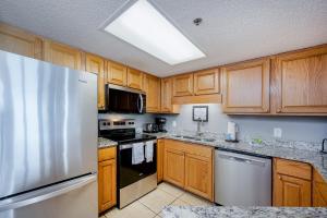 a kitchen with wooden cabinets and a stainless steel refrigerator at Phoenix VII 7709 condo in Orange Beach