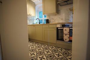 a kitchen with white cabinets and a black and white tile floor at Ground floor sea view flat Hastings in Hastings