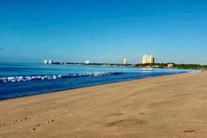 a beach with the ocean and buildings in the background at Cabana Steps From The Beach - Pool & Beach Access in Nueva Gorgona