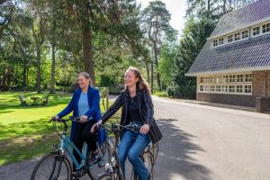 two women riding bikes down a road at Hotel Woudschoten in Zeist