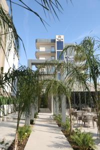 a walkway with palm trees in front of a building at Hotel Roden in Golem