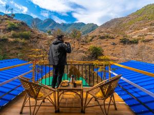 a man standing on a balcony looking out at the mountains at The Hosteller Mussoorie By the Streamside, Kempty in Mussoorie