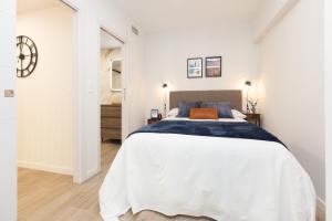 a white bedroom with a bed and a clock on the wall at Xena Cucuraza by BeValle in Panticosa