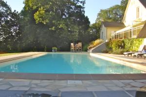 a swimming pool with blue water in a yard at La Bruyère-Maison d'hôtes-Piscine in May-sur-Orne