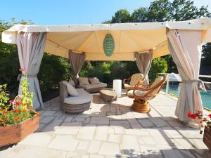a gazebo on a patio with chairs and tables at La Bruyère-Maison d'hôtes-Piscine in May-sur-Orne
