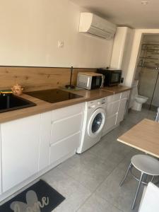 a kitchen with a sink and a washing machine at Au soleil in Canet-en-Roussillon