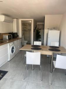 a kitchen with a wooden table and white chairs at Au soleil in Canet-en-Roussillon