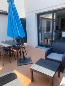 a patio with a table and a blue umbrella at Au soleil in Canet-en-Roussillon