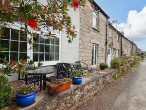 a patio with a table and chairs and potted plants at Vis Valley View in Pentewan