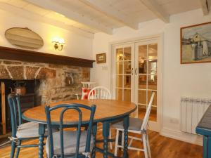 a dining room with a table and chairs and a fireplace at Vis Valley View in Pentewan