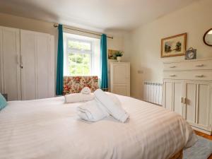 a bedroom with a large white bed with a window at Vis Valley View in Pentewan