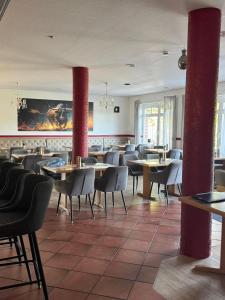 a restaurant with tables and chairs and red pillars at Mendoza Steakhaus & Hotel in Mirow