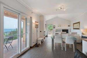a dining room and living room with a view of the ocean at Villa Capo Berta View in Diano Marina