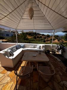 a couch and table under an umbrella on a patio at Flowerhouse in Porto Heli
