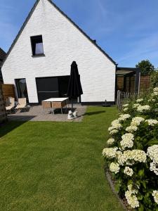 a white building with a table and an umbrella in a yard at Casa Loua in Blankenberge