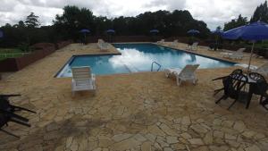a large swimming pool with chairs and umbrellas at Hotel Harmonia Sarapuí in Sarapuí