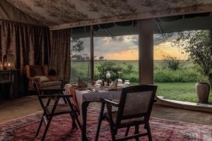 a dining room with a table and chairs and a large window at Elephant Pepper Camp in Masai Mara