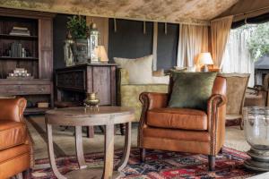 a living room with a bed and a table and chairs at Elephant Pepper Camp in Masai Mara