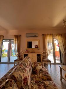 a living room with a couch and some windows at Flowerhouse in Porto Heli