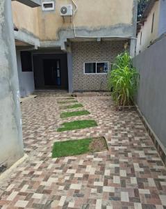 un cortile vuoto con un edificio e dell'erba di Cuic apart a Cabinda