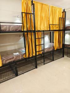 three bunk beds in a room with yellow curtains at Kerala dormitory edapally in Cochin