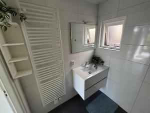 a white bathroom with a sink and a mirror at Vida Bonita in Den Burg +23 photos