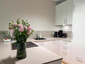 a kitchen with a vase of pink flowers on a counter at Ferienwohnung Lütte Bleev am Dümmer See in Lembruch