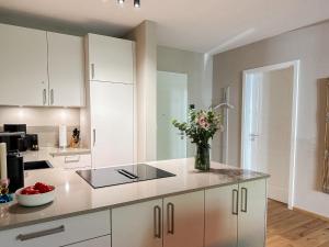 a kitchen with white cabinets and a vase of flowers at Ferienwohnung Lütte Bleev am Dümmer See in Lembruch