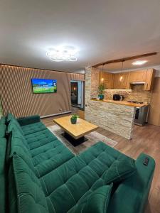 a living room with a green couch and a table at Green Escape in Slănic-Moldova