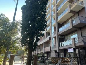 a large apartment building with a tree in front of it at Guest Apart in Ozurgetʼi