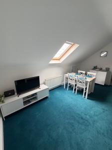 a living room with a tv and a table with chairs at Cosy East Clare Apartment in Coolcoosaun