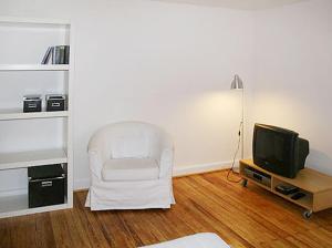 a living room with a white chair and a television at Ferienwohnung in Hamburg West in Hamburg