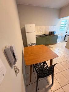 a small kitchen with a wooden table and chairs at Apart Centro 06 in Tubarão