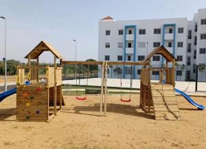 a playground with two swings and a slide at Apartment with pool in Asilah