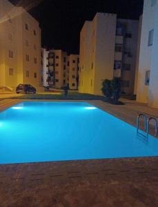 a blue swimming pool at night with buildings at Apartment with pool in Asilah