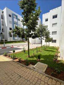 a tree in a park in front of a building at Apartment with pool in Asilah