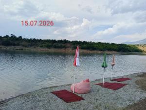 three umbrellas on the shore of a body of water at SuperPanorama GuestHouse in Kukës